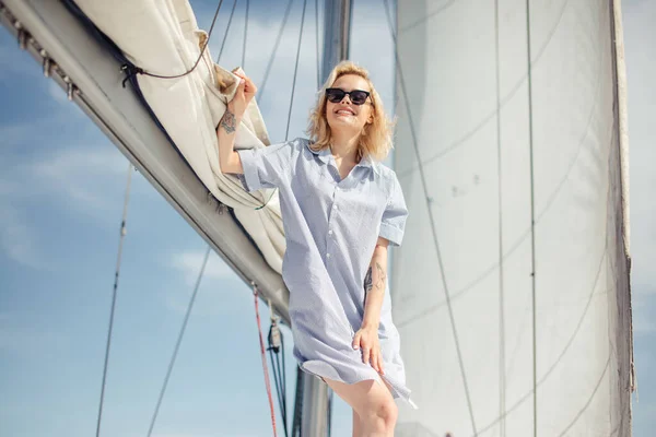 Donna su yacht bianco in tema nautico in mare aperto. Capelli biondi e vestiti blu. — Foto Stock