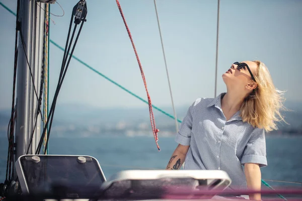 Açık denizde deniz temalı beyaz yatta bir kadın. Sarı saçlı ve mavi elbiseli..