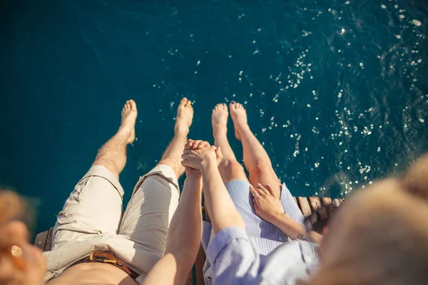 Jovem casal amoroso sentado na alimentação de barco à vela, lavar as pernas na água do mar. — Fotografia de Stock