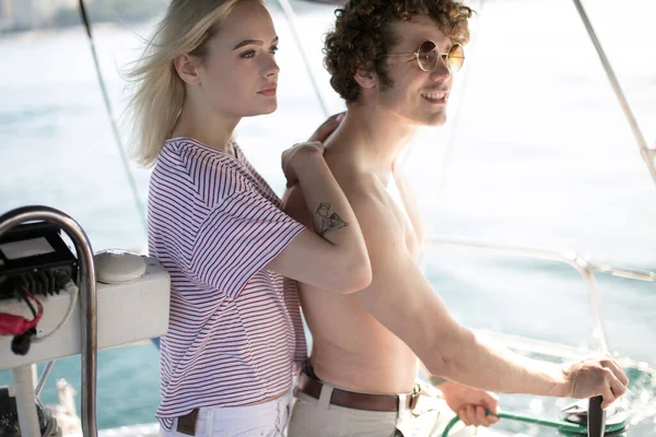 Mann mit Freundin am Ruder einer Jacht und Blick in die Ferne — Stockfoto