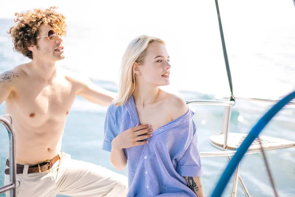 Feliz joven pareja enamorada sonriendo y disfrutando de un viaje en yate por el mar. — Foto de Stock