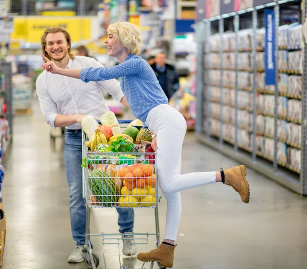 Пара наслаждается покупками в супермаркете. Женщина о поцелуе с мужчиной — стоковое фото