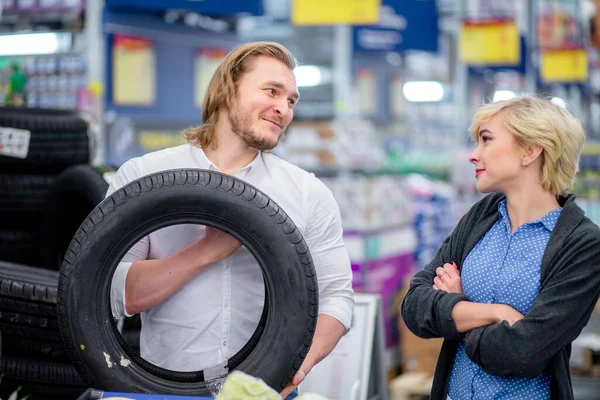 Mutlu genç çift alışveriş merkezinde araba lastikleriyle seçim yapıyor. — Stok fotoğraf