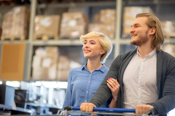 Paar wählt Waren im Supermarkt aus. Mann und Frau schieben Einkaufswagen. — Stockfoto