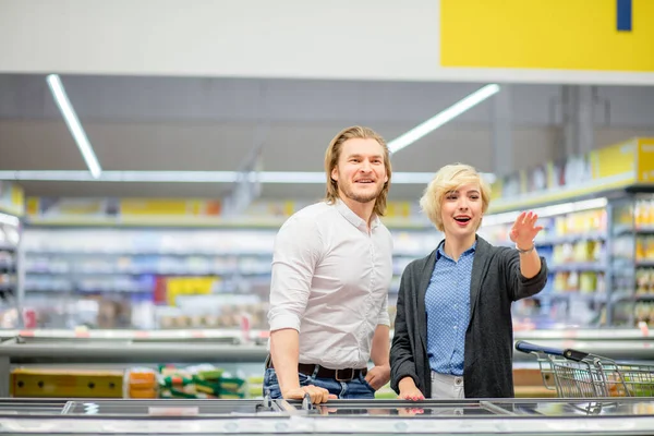 Glad kaukasiskt par väljer fryst mat i mataffären i köpcentret. — Stockfoto