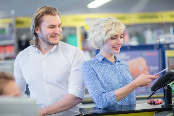 Frau an der Supermarktkasse, sie bezahlt mit Kreditkarte. — Stockfoto