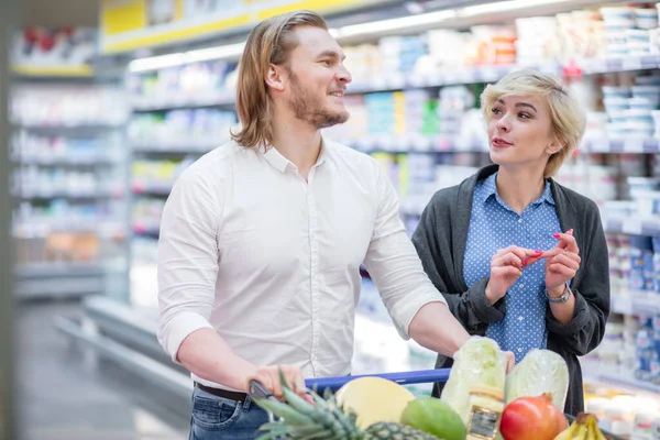 Koppel in een supermarkt winkelen met volle levensmiddelen kar kopen van boodschappen — Stockfoto
