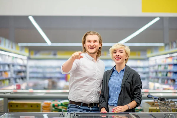 Gelukkig Kaukasisch paar kiezen bevroren voedsel bij supermarkt in winkelcentrum. — Stockfoto