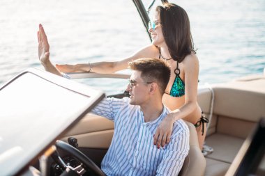 Genç evli çift motorlu teknede deniz gezintisi yapıyor.