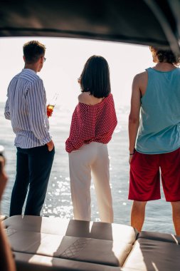 Bir grup arkadaş bir tekne gezisi sırasında güneş banyosu yapıp suda yüzerler.