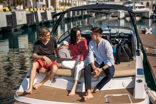 Amigos descansando no barco a motor no cais marinho, viajando em férias de verão. — Fotografia de Stock