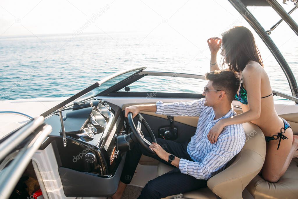 Young married couple having sea excursion on motor boat