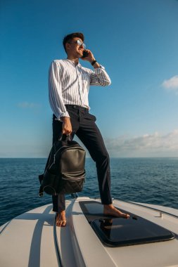 Kendine güveni tam bir yat sahibi denize açılırken iş meselelerini hallediyor.