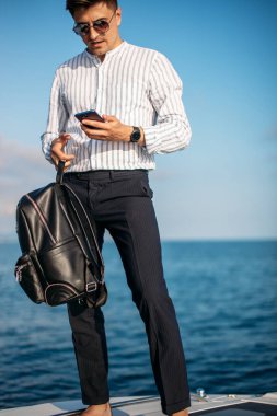 Yaz tatilinde lüks bir yatın önünde poz veren yakışıklı erkek model.