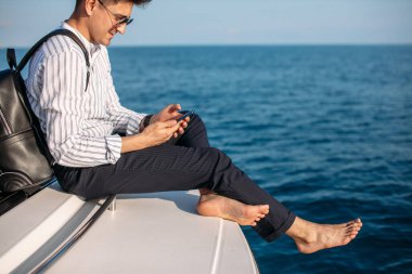 Yaz tatilinde lüks bir yatın önünde poz veren yakışıklı erkek model.