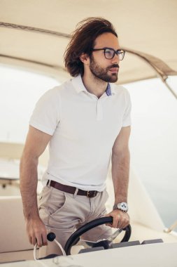 Motorlu teknesini süren yakışıklı sakallı denizci.