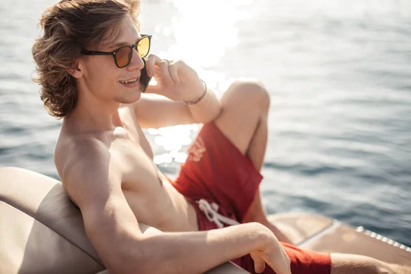 Joven chico hipster caucásico disfrutando de viaje en cubierta de yate navegando por el mar. — Foto de Stock