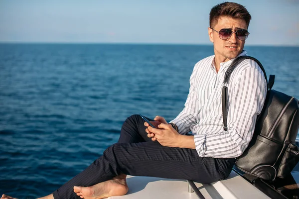 Уверенный красивый владелец яхты решает свои деловые вопросы во время плавания в море — стоковое фото