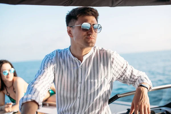Handsome male model posing in front of a luxury yacht during summer vacation