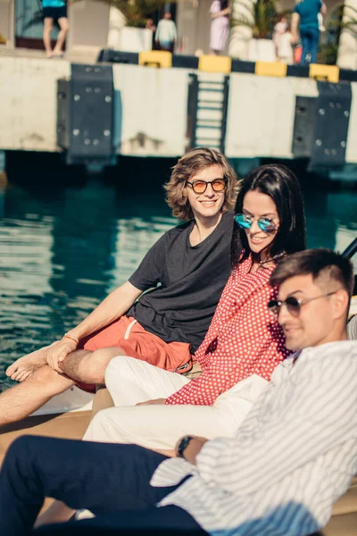 Amigos descansando no barco a motor no cais marinho, viajando em férias de verão. — Fotografia de Stock