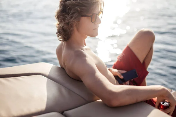 Joven chico hipster caucásico disfrutando de viaje en cubierta de yate navegando por el mar. — Foto de Stock