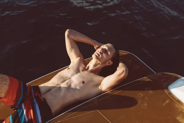 Joven chico hipster caucásico disfrutando de viaje en cubierta de yate navegando por el mar. — Foto de Stock