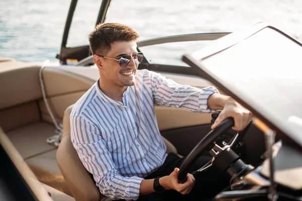 Empresário de sucesso inspirador em pé por barcos de luxo e iates contra um céu azul profundo, segurando sua jaqueta sobre o ombro. — Fotografia de Stock