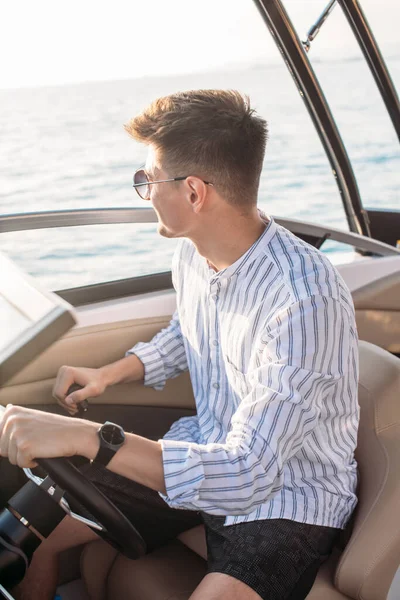 Aspirational successful businessman standing by luxury boats and yachts against a deep blue sky, holding his jacket over his shoulder. — Stock Photo, Image