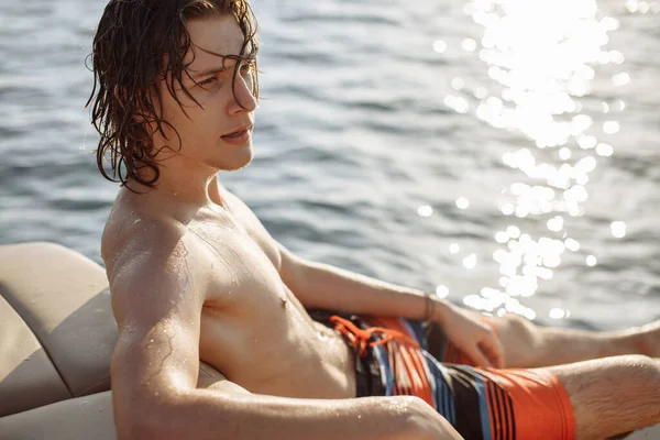 Ung kaukasisk hipster kille njuter resa på yacht däck seglar havet. — Stockfoto