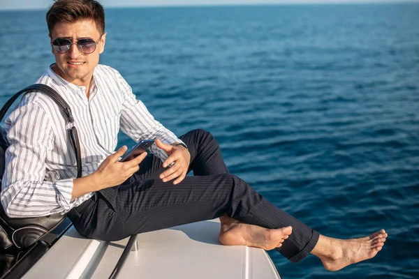 Man in sunglasses and trendy clothes sailing on motor boat — Stock Photo, Image