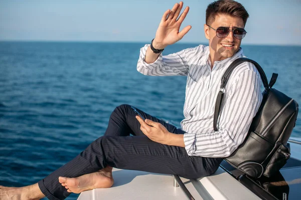 Человек в солнечных очках и модной одежде, плывущий на моторной лодке — стоковое фото
