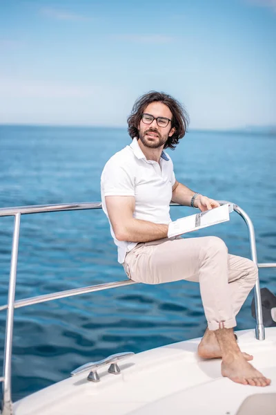 Junger bärtiger Mann auf einer Luxusjacht mit herrlichem Blick aufs Meer. — Stockfoto