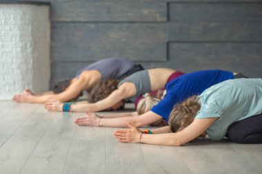 Spor salonunda ya da stüdyoda yoga yapan bir grup insan.
