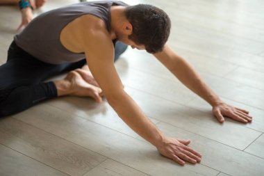 Spor erkek eğitmeni. Stüdyoda bir grup genç kadınla yoga yapıyor..