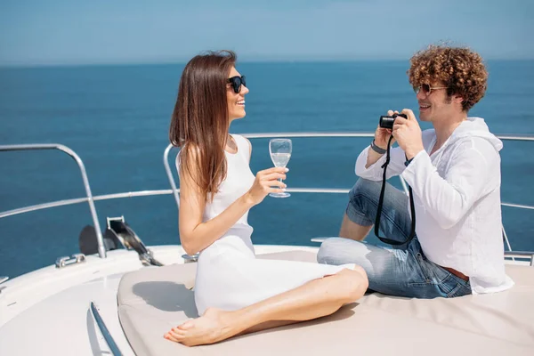 Привлекательная пара на яхте. Молодой человек фотографирует свою девушку — стоковое фото