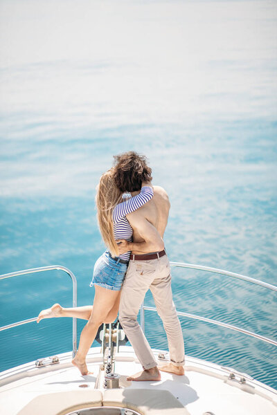 Passionate lovers dancing on bow of deck while sailing on yacht.