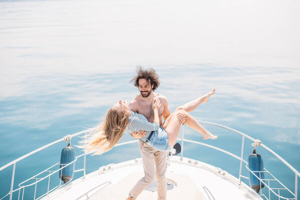 Passionate lovers dancing on bow of deck while sailing on yacht.