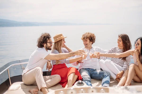 Amigos felizes batendo taças de champanhe e vela no iate — Fotografia de Stock