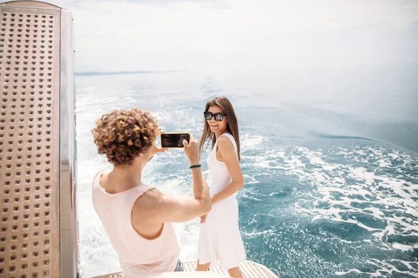 Młody fotograf robi zdjęcie swojej dziewczynie na morzu — Zdjęcie stockowe