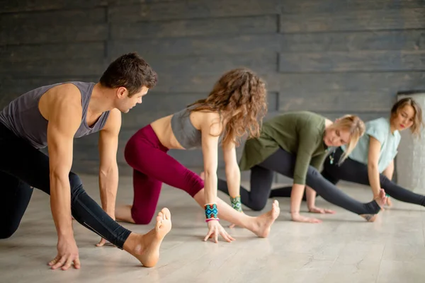 Начинающие йоги тренируются против серой стены, занимаясь йогой или осанкой пилатеса. — стоковое фото