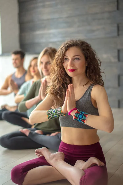 Атлетическая молодежь практикует йогу в помещении, сидя в очереди к серой стене — стоковое фото