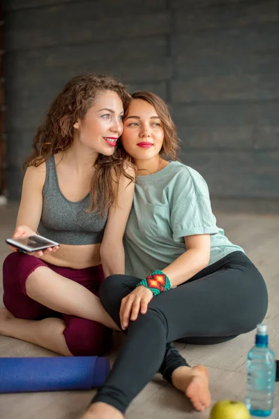 Friends relaxing after yoga. Caucasian woman sharing her photos on smartphone — Stock Photo, Image