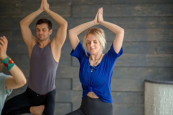 Spor salonundaki paspasın üstünde yoga egzersizleri yapan genç insanlar. — Stok fotoğraf