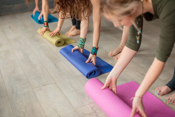 Yoga çalışmasından önce yoga yapan yoga öğrencisi kızlar stüdyoda renkli yoga minderi açıyorlar. — Stok fotoğraf