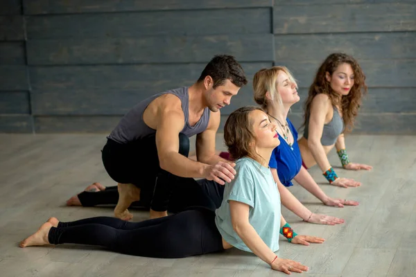 Инструктор йоги мужского пола преподает йогу трем молодым женщинам — стоковое фото