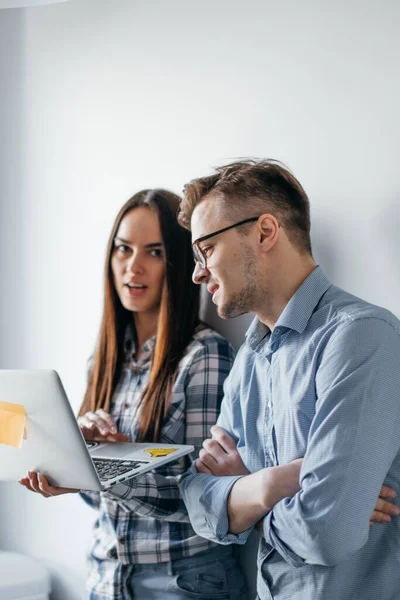 Gelukkig mix-race paar houden laptop computer terwijl staande en vieren geïsoleerd over grijze muur achtergrond — Stockfoto