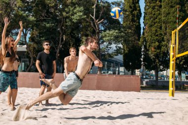 Bir grup genç plajda voleybol oynuyor.