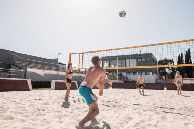 Yaz tatilinde plajda voleybol oynayan bir grup beyaz arkadaş.