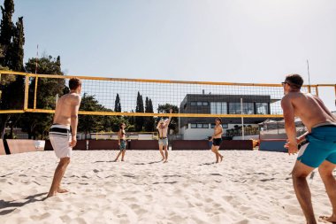 Yaz tatilinde plajda voleybol oynayan bir grup beyaz arkadaş.