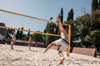 Yaz tatilinde plajda voleybol oynayan bir grup beyaz arkadaş.